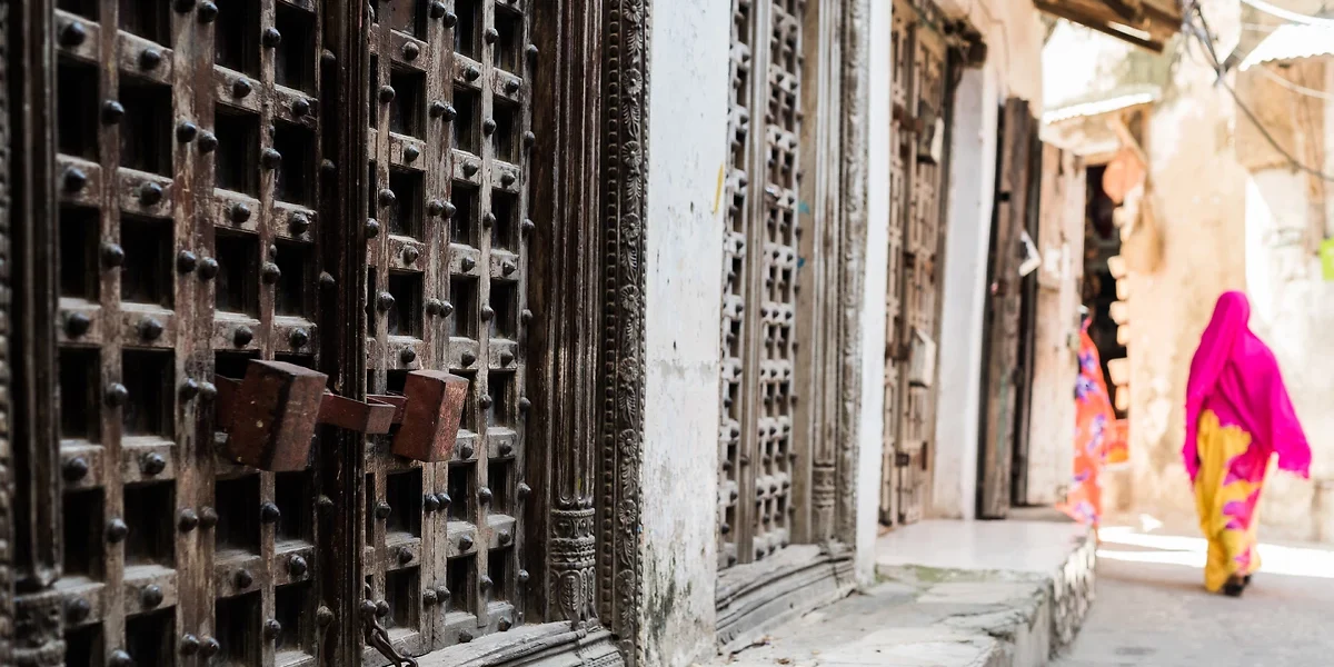 Portes anciennes et femme marchant dans la rue, Stone Town, Zanzibar