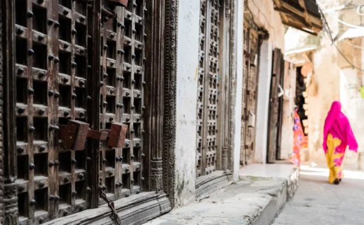 Portes anciennes et femme marchant dans la rue, Stone Town, Zanzibar